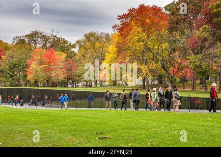 People walking past the granite wall of the Vietnam Veterans memorial inscribed with names of the U.S. armed forces who fought in The Vietnam War Stock Photo