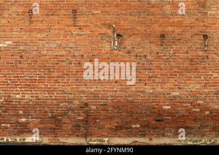 Background of expansive very old red brick wall, lower half needing to be repointed, horizontal aspect Stock Photo