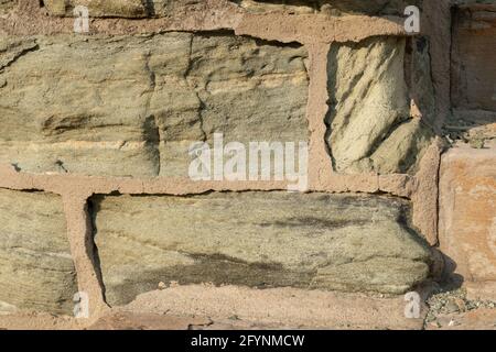 Background wall of green limestone and tan mortar, stone eaten away, horizontal aspect Stock Photo