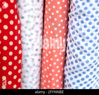 Close-up multicolored polka dotted fabrics linen cloth in rolls. Rows of minimalist red, blue and white colors. Sewing or tailoring concept. High quality vertical photo Stock Photo
