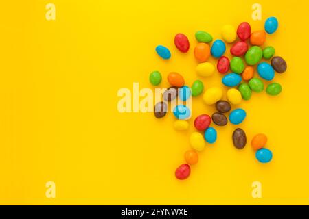 colorful candies or nuts splitted on yellow background Stock Photo