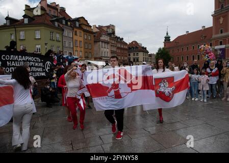 Warsaw, Warsaw, Poland. 29th May, 2021. People hold historical Belarusian flags during the Global Picket for Belarus on May 29, 2021 in Warsaw, Poland. Around a hundred of people gathered in Castles Square in the Warsaw old town to take part in the Global Picket of solidarity with Belarus. Today marks one year since the start of peaceful protests in Belarus. Credit: Aleksander Kalka/ZUMA Wire/Alamy Live News Stock Photo