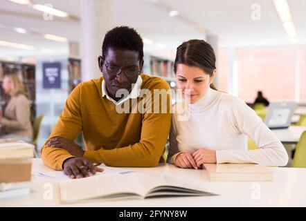 People reading and making notes while preparing for exam in library Stock Photo