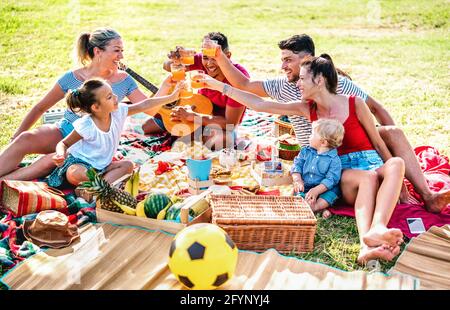 Multiracial families having fun together with kids at pic nic barbecue party - Joy and love life style concept with mixed race people toasting juices Stock Photo