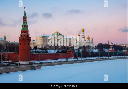 Picturesque view of architectural ensemble of Moscow Kremlin on bank of snow covered Moskva River during sunset in winter, Russia Stock Photo