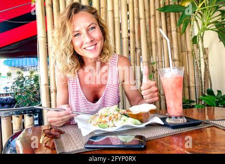 Young tourist woman eating fried rice and drinking fruit smoothie at thai restaurant in Phuket Thailand - Gastronomy travel concept Stock Photo