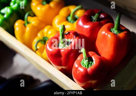 Red, green and yellow bell peppers in the vegetable box at the market. Stock Photo