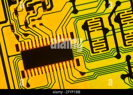 Vibrant coloured abstract macro shot of an opaque printed circuit board / pcb showing tracks / wire traces lit from behind. See NOTES. Stock Photo
