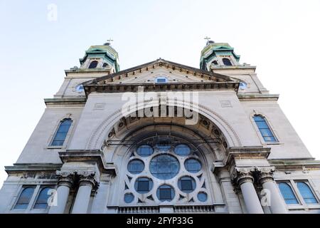 Straight on view of a gray stone church with verdigris copper cupolas, rose window, horizontal aspect Stock Photo