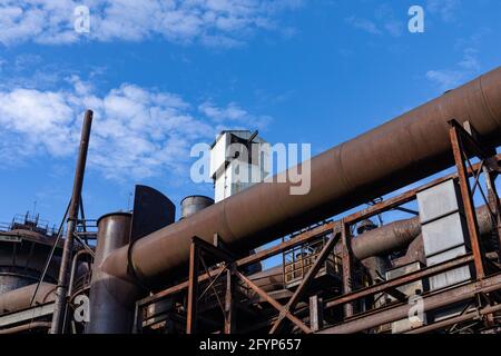 Rusting metal exterior of an old industrial site against a brilliant blue sky, industrial landscape, horizontal aspect Stock Photo