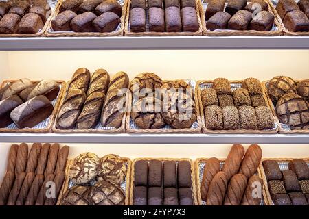 Freshly baked traditional dark bread in a baker shop. Different types of brown bread loaves on bakery shelves. Stock Photo
