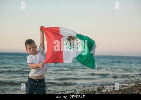 Young boy holding flag of Mexico at the Sea'September 16. Independence Day of Mexico'. Stock Photo