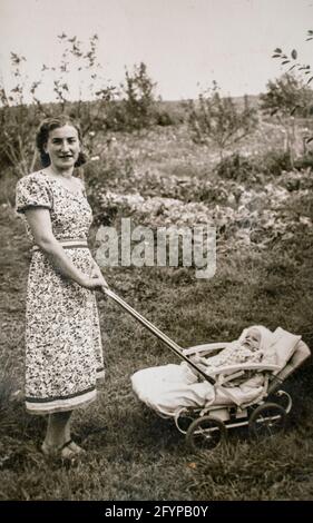 Germany - CIRCA 1930s: Portrait of mother and baby in carriage. Young female and baby in stroller pram. Vintage historical archive photo Stock Photo