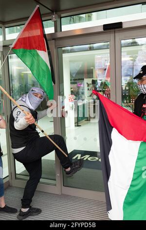 Protester kicks at BBC studio door.Protestors gather at Media City, Salford, Greater Manchester UK. The Demonstration started at 12pm 29 May 2021. The protest was to show support for the Palestinian people and against the recent escalation of conflict in the region. In Palestine the Palestinian people have faced a constant barrage from Israel following rockets fired from Gaza by the ruling Hamas militant group.  Picture: Gary Roberts/worldwidefeatures.com Stock Photo