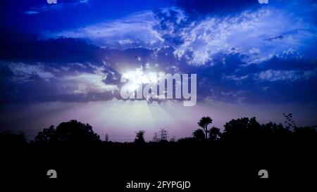 Amazing view of sunset seascape with dramatic sky and colorful clouds. Purple with orange sunset in overcast blue sky with sun rays light. Stock Photo