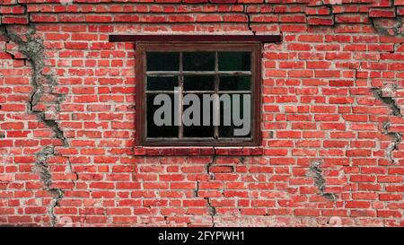 An old house in cracks, a scary wall with a wooden window. Old brick wall with cracks. Stock Photo