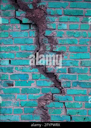 Texture of a brick wall with cracks in turquoise color. The destroyed ancient wall is turquoise. Brick background copy space. Stock Photo