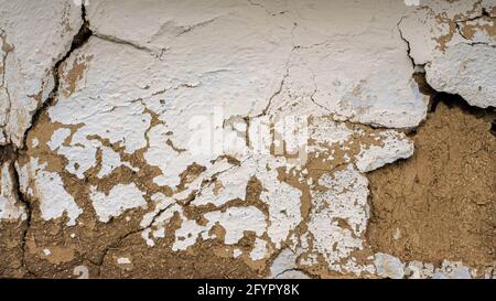 Texture of an old wall made of clay and white paint. The background is a destroyed wall, the texture of the old wooden wall. Stock Photo