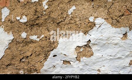 The texture of the hut is old. Ancient wall of clay and straw. Ancient wall of an old house. Background peeled paint on the wall. Stock Photo