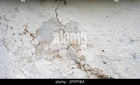 White wall with cracks with peeling paint, texture of an old wall. Copy the antique space. Stock Photo