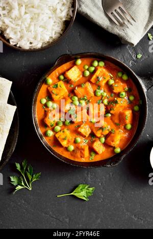 Paneer butter masala. Indian style cottage cheese curry in pan on black stone background. Top view, flat lay Stock Photo
