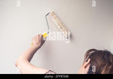 woman applies the white textured plaster to wall Stock Photo