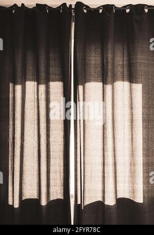 black curtain drapes closed on sunny window Stock Photo