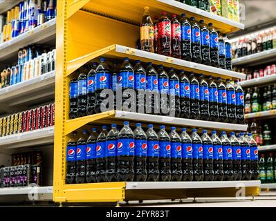 Pepsi Cola in plastic bottles stacked on supermarket rack Stock Photo