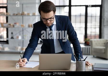 Serious busy business leader signing legal document at workplace Stock Photo