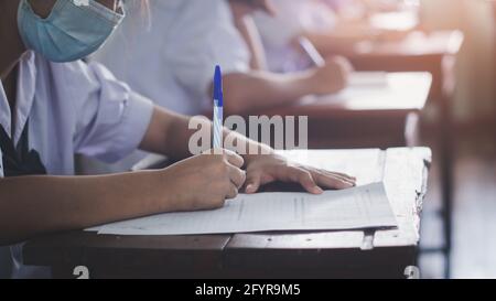 Students wearing mask for protect corona virus or covid-19 and doing exam in classroom with stress Stock Photo