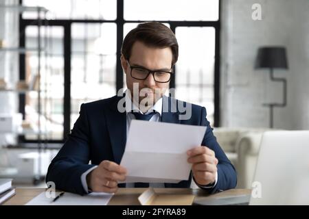 Focused business leader in formal suit and glasses reading letter Stock Photo
