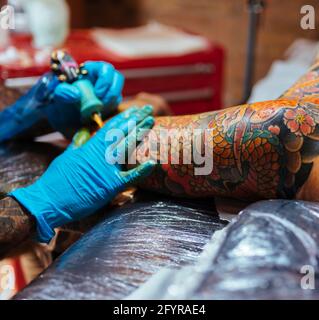 Detail of an artist's hands tattooing a japanese tattoo Stock Photo