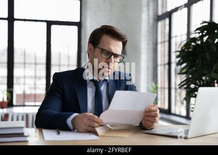 Worried confused businessman reading letter at workplace Stock Photo
