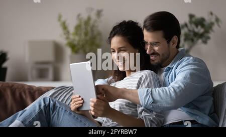 Smiling multiracial couple use tablet talk on webcam call Stock Photo