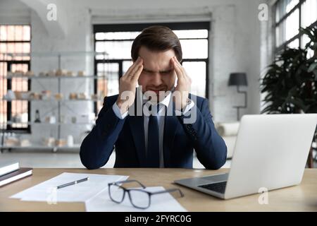 Stressed tired businessman is suffering from headache Stock Photo