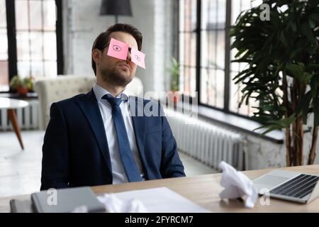 Exhausted bored manager sleeping with comic paper notes on eyes Stock Photo