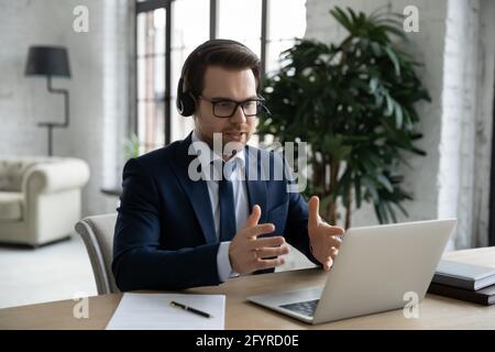 Manager in headset using laptop for video call, giving consultation Stock Photo