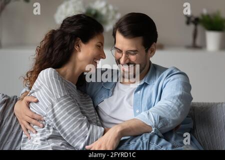 Smiling multiracial couple relax on couch enjoying weekend Stock Photo