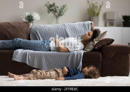 Tired young mom and small kid fall asleep at home Stock Photo