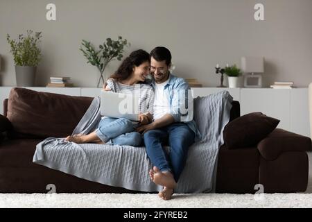 Happy multiracial couple relax at home with laptop Stock Photo