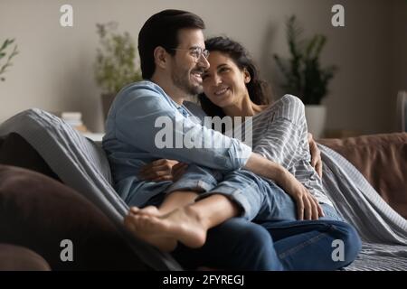 Happy multiracial couple relax at home hugging Stock Photo