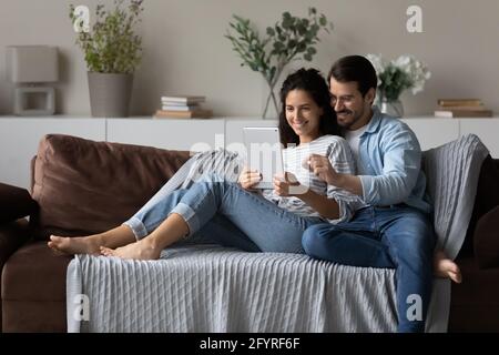 Smiling multiracial couple use tablet talking on video call Stock Photo