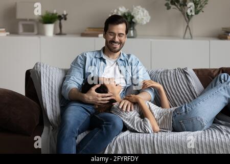 Happy multiethnic couple relax on couch hugging Stock Photo