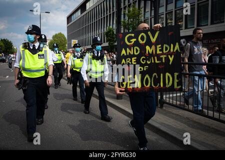 Manchester, UK. 29th May, 2021. A protester with a placard lets the police march past during a anti-lockdown protest. The number of people attending the protests has increased month on month since the introduction of the COVID-19 restrictions. Credit: Andy Barton/Alamy Live News Stock Photo