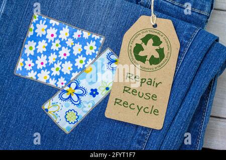 Sustainable fashion label on repaired jeans, sustainable fashion visible mending concept, repair, reuse, recycle, clothes and textiles to reduce waste Stock Photo