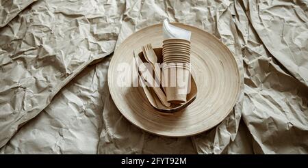 Disposable cups, forks, knives on a paper background. Stock Photo