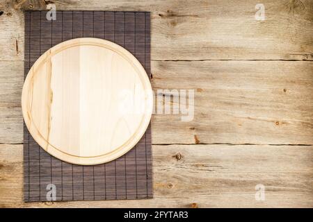 Background with wooden pizza board with bamboo table placemat over grunge rustic background Stock Photo