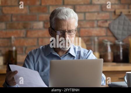 Older man holding bill makes internet payment through e-banking app Stock Photo