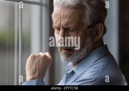 Closeup sad older man face standing indoor with eyes closed Stock Photo