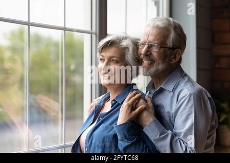 Dreamy serene mature spouses looking out the window Stock Photo